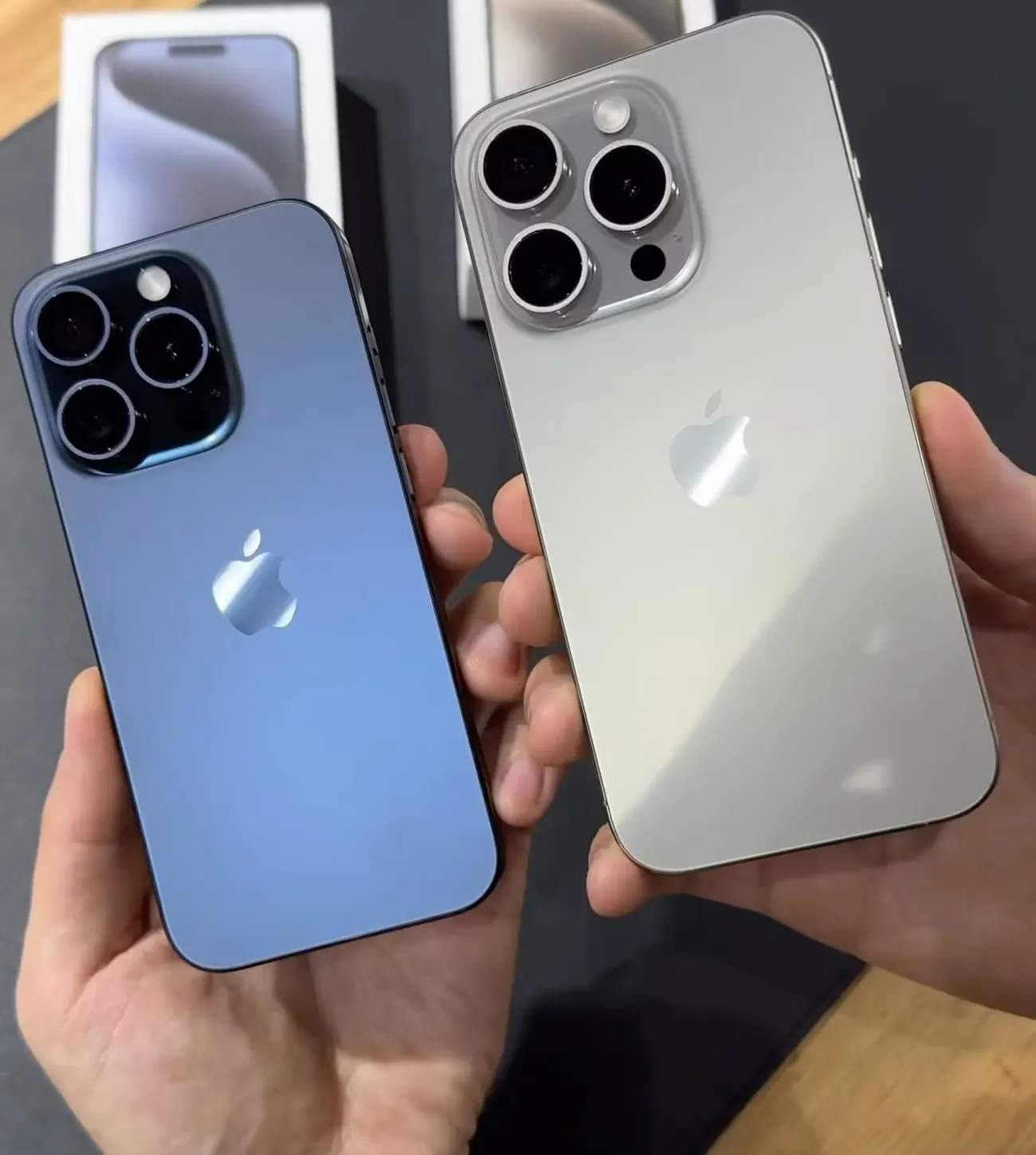 Dois iPhones Pro de titânio nas mãos, fotografia da GDL